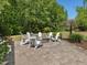 Outdoor stone firepit encircled by a brick patio and six white Adirondack chairs in a landscaped backyard setting at 1701 Bodwin Ln, Apex, NC 27502