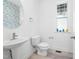 Well-lit half bathroom with a pedestal sink, white toilet, and a round mirror with decorative wallpaper at 1813 Lost Creek Ct, Apex, NC 27539