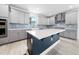 A modern kitchen features stainless steel appliances, grey cabinets, and a dark blue island with a white countertop at 1813 Lost Creek Ct, Apex, NC 27539