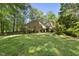 Backyard with a brick home surrounded by lush greenery, offering a private and serene outdoor setting at 2001 Lovdal Dr, Raleigh, NC 27613