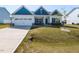 Charming single Gathering home showcasing blue and white color palette, a two car garage, and manicured front lawn at 218 E Tecoma Ln, Clayton, NC 27520
