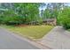 A brick home with manicured lawn and mature trees lining the driveway at 2508 Sevier St, Durham, NC 27705
