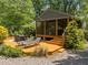 Beautiful backyard with a wooden deck, outdoor seating, lounge chairs, lush landscaping, and screened in porch at 2529 Remington Rd, Raleigh, NC 27610