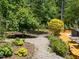Landscaped backyard featuring lush greenery, a gravel path, and a welcoming outdoor dining area on the deck at 2529 Remington Rd, Raleigh, NC 27610