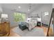 Cozy bedroom featuring hardwood floors, a ceiling fan, and a large window overlooking the lush greenery at 2529 Remington Rd, Raleigh, NC 27610