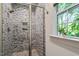 Updated tiled shower with glass door and a window offering natural light at 2613 Bedford Ave, Raleigh, NC 27607