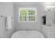 Bright bathroom with window, soaking tub, white vanity, and marble countertop at 2993 Club Dr, Raleigh, NC 27613