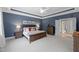 Bedroom with tray ceiling, blue walls, hardwood furniture, and an open doorway to an adjacent room at 2993 Club Dr, Raleigh, NC 27613