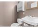 Compact powder room featuring a sink, toilet, mirrored vanity, and a storage cabinet at 3029 Wycliff Rd, Raleigh, NC 27607