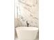 Modern bathroom with a luxurious white soaking tub and stunning marble accent wall at 305 W Waddell St, Selma, NC 27576