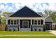 Charming navy home featuring a covered porch, white trim, and well-manicured landscaping at 305 W Waddell St, Selma, NC 27576