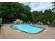 Community pool with sun loungers, chairs, tables, and lush trees in the background at 3258 Yorkshire Cir, Sanford, NC 27332