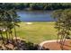 Scenic golf course view with lake backdrop and well-maintained green, bordered by mature trees and a paved path at 3258 Yorkshire Cir, Sanford, NC 27332
