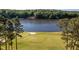 Scenic golf course view with lake backdrop and well-maintained green, bordered by mature trees and a paved path at 3258 Yorkshire Cir, Sanford, NC 27332