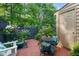 Charming brick patio with mature landscaping, a table and chairs, and a small storage building at 35 Stonewall Way, Durham, NC 27704