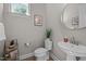 Compact powder room with a modern sink, toilet, round mirror, and decor at 403 Prestwood Dr, Hillsborough, NC 27278