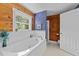 This spa-like bathroom features a whirlpool tub, natural light, and wood-paneled walls at 407 Howard Tant Rd, Zebulon, NC 27597