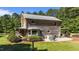 Charming log home with a metal roof, outdoor seating area, and lush green lawn surrounded by trees at 407 Howard Tant Rd, Zebulon, NC 27597