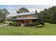 Exterior view highlighting covered porch and manicured landscaping of the log cabin at 407 Howard Tant Rd, Zebulon, NC 27597