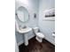 Stylish powder room featuring a pedestal sink, oval mirror, and decorative wall art at 409 Eagle Ct, Henderson, NC 27536