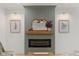 Striking fireplace featuring a wooden mantle and adjacent artwork, flanked by modern sconces at 42 Turkey Ct, Timberlake, NC 27583