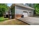 Side exterior of home featuring a two-car garage, propane tank, and backyard access at 450 S Stratford Dr, Henderson, NC 27537