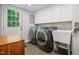 Well-lit laundry room with modern washer and dryer, utility sink, white cabinets, and exterior access to the backyard at 526 Colony Woods Dr, Chapel Hill, NC 27517