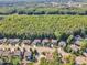A high angle view of a residential neighborhood nestled beside a lush green forest, showing tree coverage at 533 Opposition Way, Wake Forest, NC 27587
