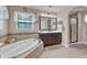 This bathroom features a tiled tub surround, shower, framed mirror over vanity, neutral walls and flooring at 533 Opposition Way, Wake Forest, NC 27587