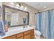 Bright bathroom featuring a wood vanity, neutral walls, large mirror, and a blue and white shower curtain at 533 Opposition Way, Wake Forest, NC 27587