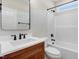 Bathroom with modern vanity, mirror, wood-look cabinet, bathtub with shower, and window at 56 Birchtop Cir, Zebulon, NC 27597