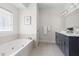 Bright bathroom features a large soaking tub, neutral tile surround, and vanity at 608 Elin Ct, Hillsborough, NC 27278