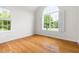 Sunlit bedroom with hardwood floors, large arched window, and white trim at 608 Elin Ct, Hillsborough, NC 27278