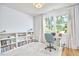 Bright home office featuring a built-in bookcase, large window, and comfortable workspace with hardwood floors at 631 Linfield Dr, Durham, NC 27701