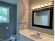 Bright bathroom with a white vanity, cream sink, and a framed mirror with decorative lighting above at 703 W Church St, Angier, NC 27501