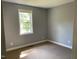 A quiet bedroom with grey walls, carpeted flooring, and a bright window that allows natural light to come in at 703 W Church St, Angier, NC 27501