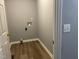 An empty laundry room with grey walls, light-wood colored floors, and hookups ready for a washer and dryer at 703 W Church St, Angier, NC 27501