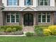 Inviting front entrance with a stone porch, adorned with hanging floral arrangements at 7312 Hasentree Way, Wake Forest, NC 27587