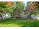 Landscaped backyard featuring a well-maintained lawn, mature trees, a deck, and white picket fence at 9251 Palm Bay Cir, Raleigh, NC 27617