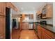 Well-lit kitchen featuring stainless steel appliances, warm wood cabinets, and dark countertops at 1000 Lamond Ave, Durham, NC 27701