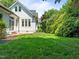 Lush green backyard featuring manicured lawns, mature trees, and architectural details of the home at 10003 Fountain, Chapel Hill, NC 27517