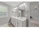 Bathroom featuring double sink vanity, stylish mirrors, and ample natural light from the window at 104 Anderson Park Dr, Wake Forest, NC 27596