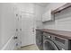 Functional laundry room with modern washer and dryer, storage cabinets, and convenient access to the exterior at 104 Anderson Park Dr, Wake Forest, NC 27596