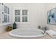 Bright bathroom with a white tub, shuttered windows, and neutral stone surround at 106 Clendenen Ct, Cary, NC 27513