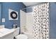 Bathroom featuring blue textured wallpaper, a white polka dot shower curtain, and white tiled bathtub at 106 Clendenen Ct, Cary, NC 27513