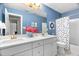 Bright bathroom with a dual sink vanity, textured blue walls, and a tub with a polka dot shower curtain at 106 Clendenen Ct, Cary, NC 27513