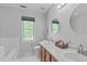 Bright bathroom featuring a double vanity, tub with tile surround, and window at 110 Ferris Wheel Ct, Cary, NC 27513