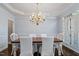 Dining room with chandelier lighting, wainscoting, and views of the backyard through shuttered windows at 112 Glenspring Way, Morrisville, NC 27560