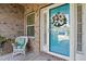 Close-up of front door, adorned with a wreath, and wicker chair on a brick-paved porch at 116 Colonade Ct, Benson, NC 27504