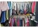 Walk-in closet with organized hanging rods and shelves filled with colorful clothing at 116 Colonade Ct, Benson, NC 27504